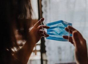 Woman is holding a COVID-19 anti-coronavirus mask as protection against infection
